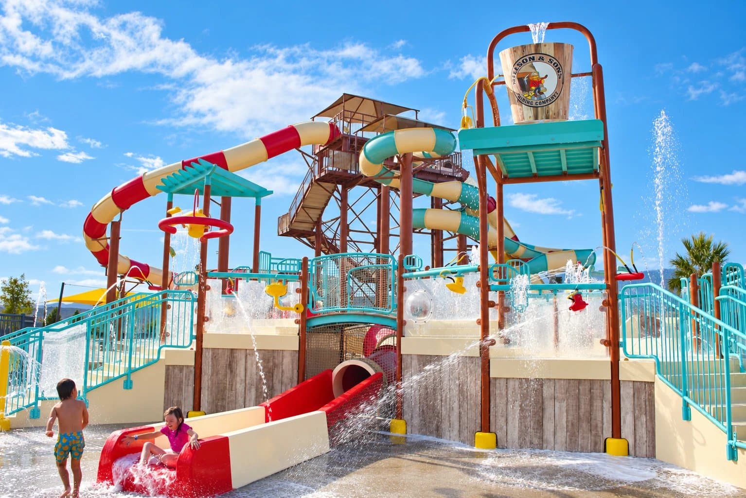 Kids on the splash ground slide below the bucket tower and water slides