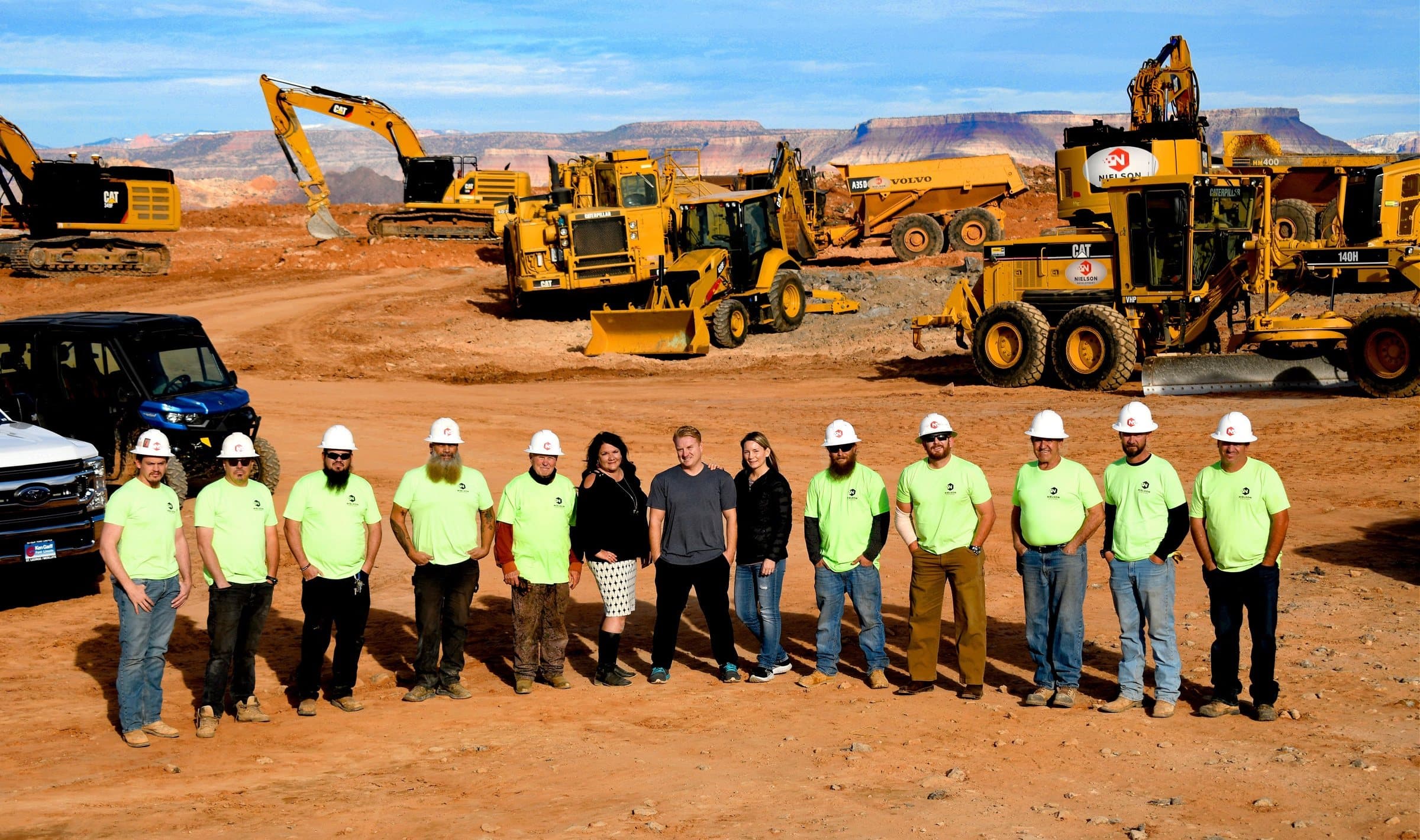 The Nielson Development crew in hard hats in front of their own Caterpillar fleet on a Southern Utah job site